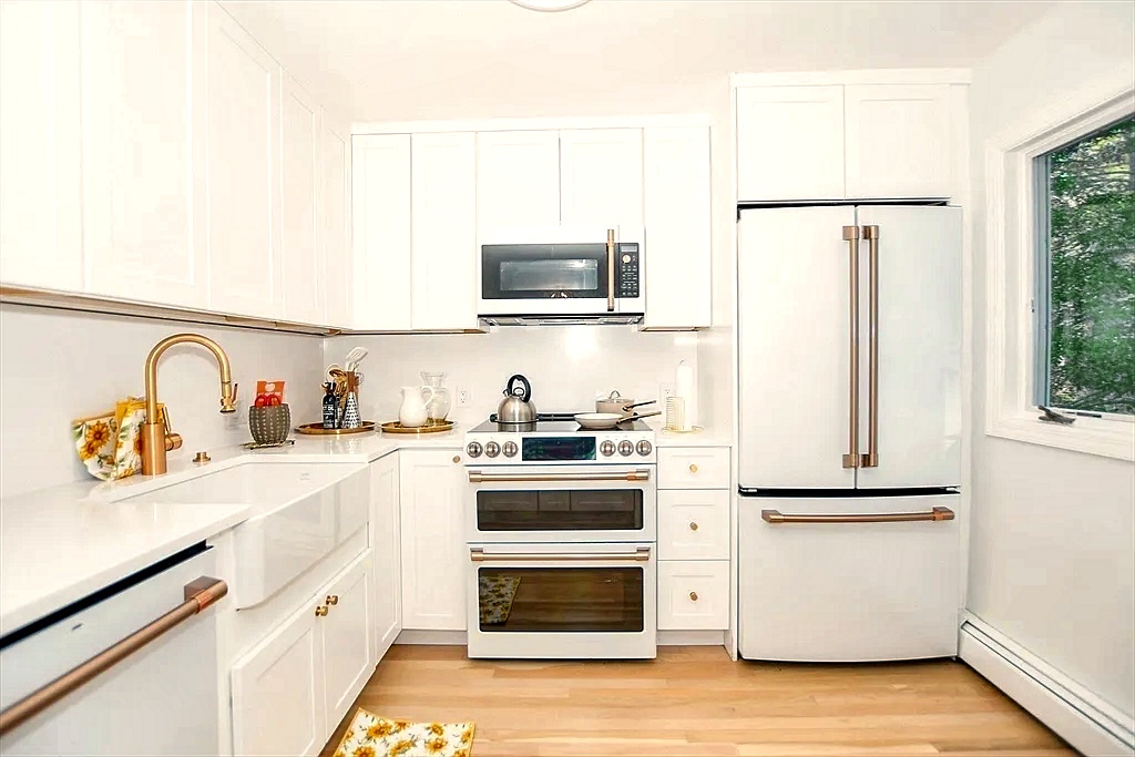 Renovated coastal kitchen with white cabinetry, quartz countertops, breakfast bar and recessed lighting.