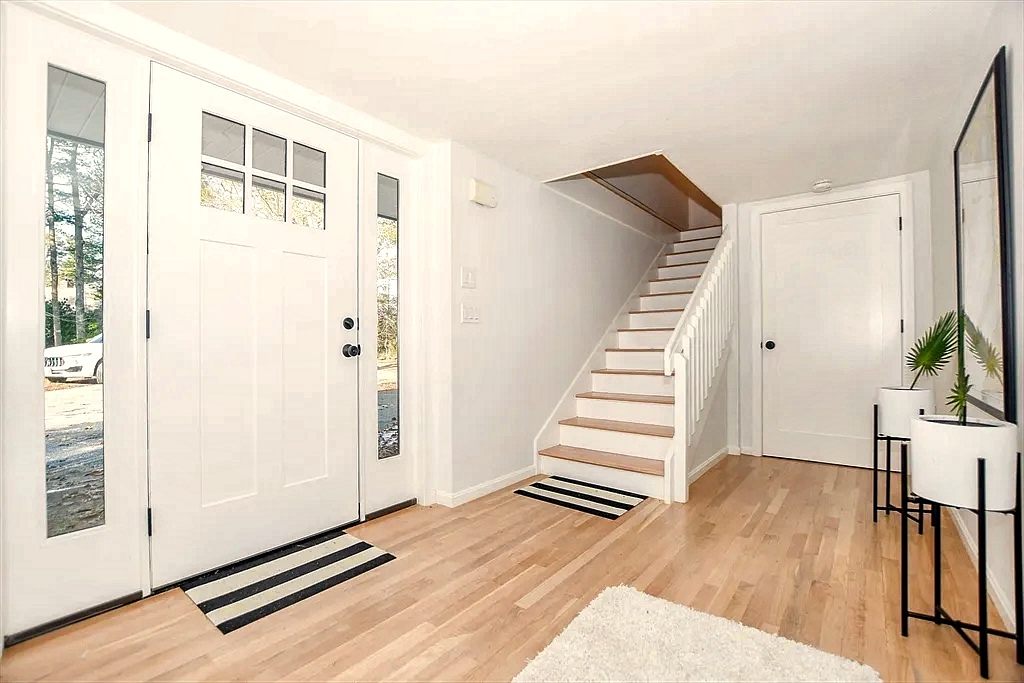 Coastal entry hall with white staircase leading upstairs to the primary suite.
