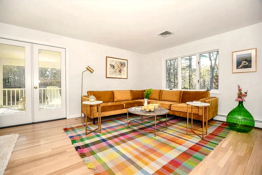 Living area with hardwood floors and tall windows filled with soft coastal afternoon light.